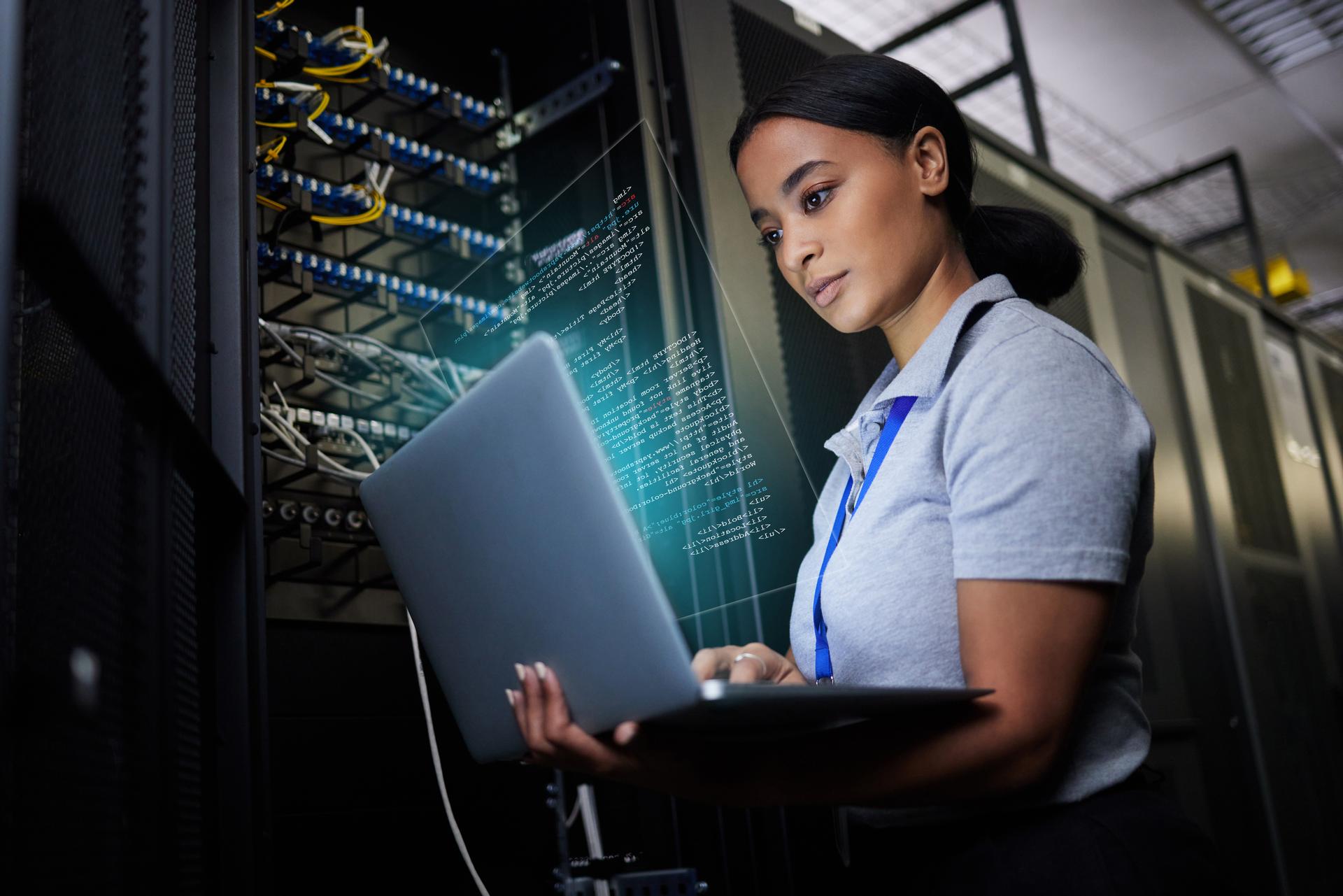 Laptop, network and data center with a black woman it support engineer working in a dark server room. Computer, cybersecurity and analytics with a female programmer problem solving or troubleshooting