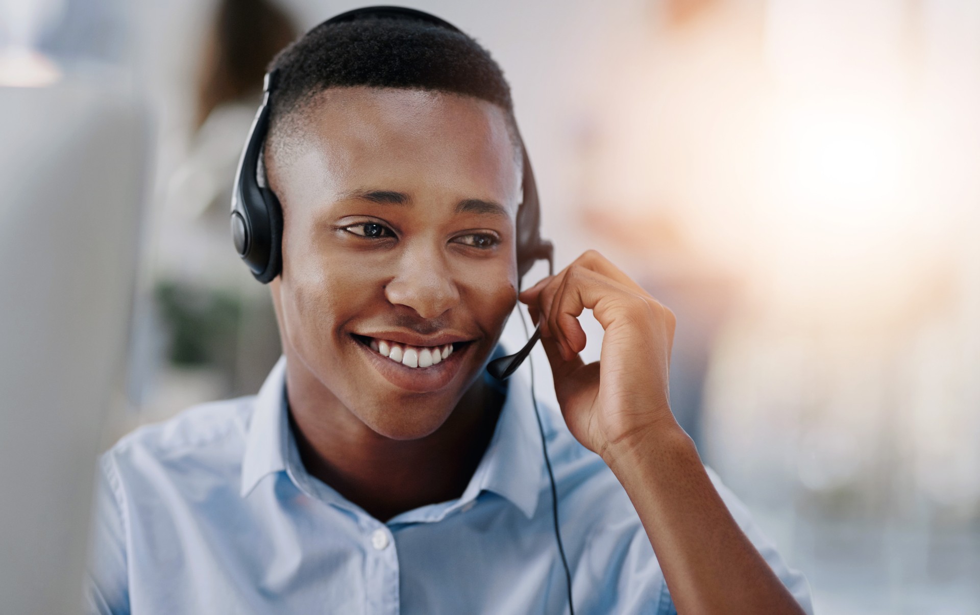 Call center, headset and black man with smile, telemarketing and consultant in office and talking. Business, tech support and agent with conversation, help desk and communication for sales in startup