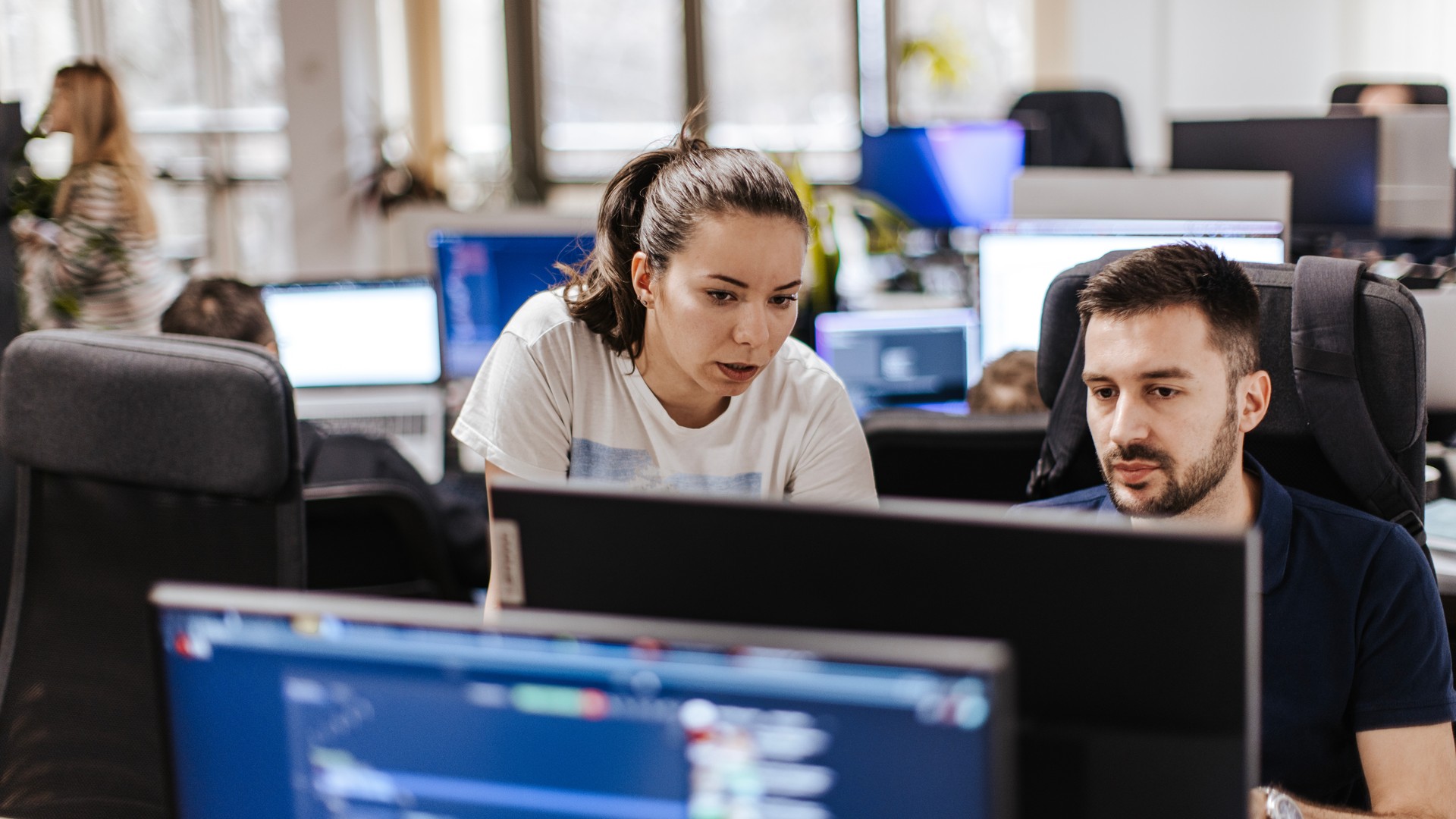 Female and male Caucasian developers working on a computer at the open space office